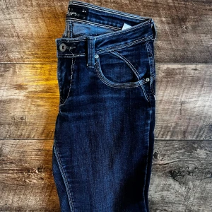 Mörkblå Lee jeans storlek 27 - Snygga mörkblå jeansbyxor från Lee. Byxorna har låg midja och är tillverkade i bomull med lite elastan för extra komfort. Perfekta för en avslappnad och trendig look. Mycket fint skick. 
