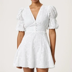 ADOORE Vit blommig kortklänning med puffärm - Klänning från ADOORE helt ny med prislappar! Endast testad. Nypris 1495kr. Säljer då den blev för liten så jag köpte en ny men kunde då inte längre lämna tillbaka. Skriv för egna bilder!