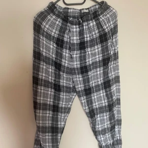 Svartvita rutiga byxor - Säljer ett par svartvita rutiga byxor med resår i midjan. Byxorna har en avslappnad passform och är perfekta för en chill stil. Mjukt material och smala benslut för en modern look.🤍🖤