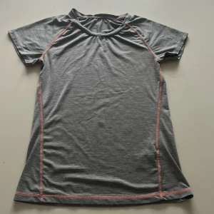 Grå sport t-shirt från H&M - Grå sport t-shirt från H&M med rosa sömmar. Tillverkad i ett mjukt och stretchigt material som passar perfekt för träning. Klassisk passform med korta ärmar och rund halsringning. Kommer inte till användning🤍