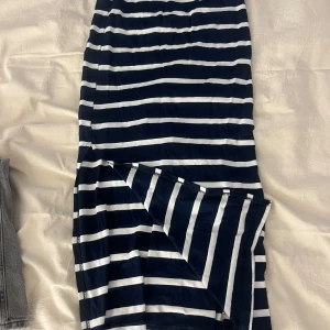 Marinblå och vit randig långkjol  - Säljer en långkjol med marinblå och vita horisontella ränder. Kjolen har en tight passform och en slits bak för extra rörelsefrihet. Perfekt för dig som gillar en stilren och klassisk look.