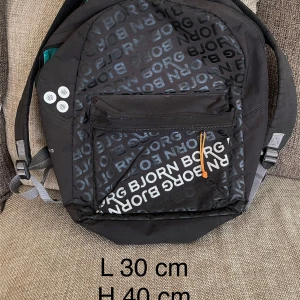 Vintage/ retro ryggsäck från Björn Borg i nyskick  - Den här coola och snygga ryggsäcken från Björn Borg har massa små, smarta detaljer och lösningar. Den har 2 stora fack med blixtlås och i facket mot ryggsäckens baksida finns vaddering inuti ”väggarna” och det finns speciell anordning för att frakta sin dator tex.  I det främre facket finns en påsydd ficka i vattenavvisande material, med blixtlås. På den fickan finns ett ogenomskinligt nät med olika storlekar på sina fack. På ryggsäckens framsida finns en extra ficka som är mycket rymlig