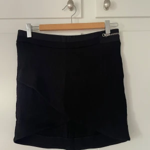 Svart omlottkjol med dragkedja - Säljer en svart kort omlottkjol med synlig dragkedja bak och dekorativ dragkedja fram. 