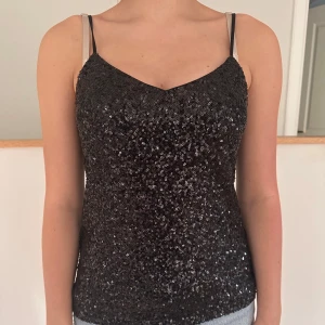Svart glittrig linnetopp - Säljer en svart glittrig linnetopp med smala axelband. Jättefin och endast använd en gång!