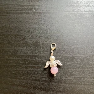 Ängelhänge med pärlor och rosa detalj🩷 - Säljer ett sött hänge format som en ängel med silverfärgade vingar, vita pärlor och en rosa pärla. Perfekt som accessoar till halsband eller armband. Fästes enkelt med karbinhake.🩷