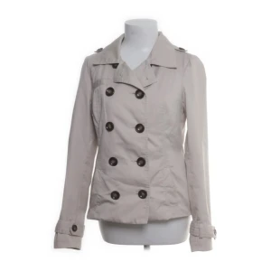 Beige trenchcoat  - Stilren beige trenchcoat från Vero Moda med dubbelknäppning och stora svarta knappar. Den är i super bra skick och sitter åt lite i midjan på ryggen så den ger fin form :) Perfekt för vår, sommar och höst.
