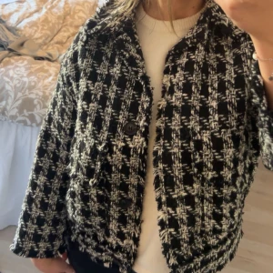Svartvit rutig vårjacka med knapp - Säljer en svartvit vårjacka med rutigt mönster och en knapp framtill. Jackan har krage och är långärmad, perfekt för att ge en stilren touch till din outfit.💗