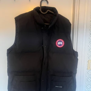 Svart dunväst från Canada Goose - Säljer min canada goose väst då jag inte använder den, har inte användt 3 månader. finns inga fel med den, såklart är den äkta, köpte den på johnells i nyköping. pris 3000:- skickas samma dag som köpet genomförs. 