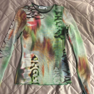 Meshtröja med färgglatt mönster från Weekday - Säljer en långärmad meshtröja från Weekday i storlek XS. Tröjan har ett färgstarkt abstrakt mönster i grönt, orange, svart och vitt. Tight passform och tunn, genomskinlig mesh som ger en cool och trendig look.