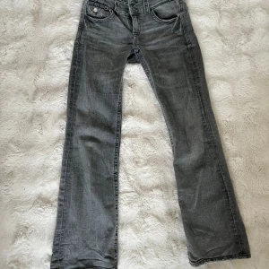 Grå bootcut jeans från Gina Tricot - Säljer ett par gråa bootcut jeans från Gina Tricot. Jeansen har klassisk femficksdesign, låg midja och raka ben som går ut lite nertill. Perfekta för dig som gillar en avslappnad och tidlös stil.