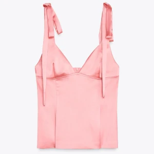 Rosa satintopp med knytband - Supersöt rosa satintopp med rosetter, ifrån Zara i storlek M, säljer då jag beställde fel storlek. Aldrig använd🎀🎀Pris lapp sitter kvar. ( säljer den endast för original pris då jag inte använt den)