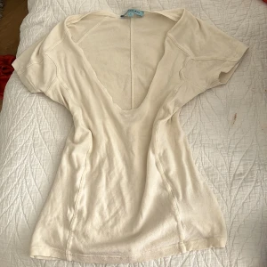 Vit v-ringad topp från Guess - Säljer en vit topp från Guess med djup v-ringning och korta ärmar. Modellen är figurnära och tillverkad i ett mjukt bomullsmaterial. Perfekt för dig som gillar stilrena och enkla plagg. Priset kan diskuteras