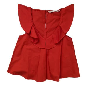 Röd volangtopp med v-ringning - Säljer en röd topp med volangdetaljer och v-ringning. Toppen har korta ärmar med volang och knäppning bak. Perfekt för dig som vill sticka ut med en färgstark och trendig look.