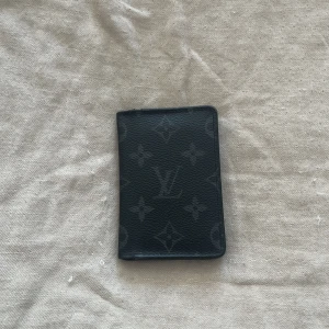 Svart plånbok från Louis Vuitton - Säljer en svart plånbok från Louis Vuitton med klassiskt monogrammönster. Plånboken har flera kortfack och är tillverkad i skinn. Perfekt för dig som vill ha en stilren och lyxig accessoar.