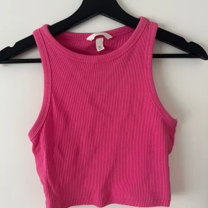 Rosa ribbad croppad linnetopp från H&M - Säljer en rosa ribbad croppad linnetopp från H&M. Toppen har en tight passform och är ärmlös med rund halsringning. Perfekt för varma dagar i sommar💗💗