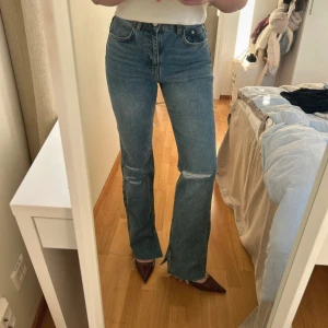 Blå jeans med slits och slitningar - Jeans från Pull&Bear med slits vid fötterna och slitningar på knäna och lite på rumpan. Jag är 168 cm lång + 5 cm klackar på bilden med innerbenslängd 83 cm. Jättefint skick! 🩵