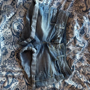 Blå jeansshorts från Terranova - Säljer ett par klassiska blå jeansshorts från Terranova i storlek XS. De har upprullade benslut,  fickor och snygga slitningar för en avslappnad look. Perfekta för varma dagar och enkla att matcha med allt.