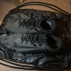Svarta och gråa Nike fotbollsskor - Säljer ett par snygga fotbollsskor från Nike! Det är ett par mercurials i väldigt bra skick, använda bara ett få tal gånger därav priset!! Skorna kommer med en påse som ni kan se på en av bilderna.Det är bara att lägga bud så svarar jag så snabbt som möjligt! Hör av er vid funderingar!!