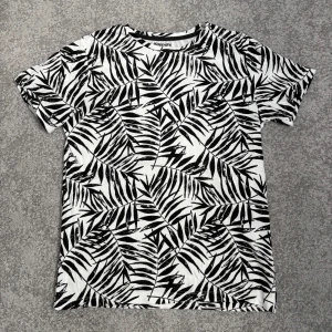 Svartvit t-shirt med bladmönster - T-shirt från KappAhl med svartvitt bladmönster. Den har inga fläckar och knappt använd!