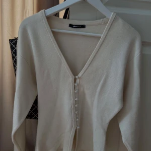 Beige kofta med knappar från Gina Tricot - Säljer en stilren beige kofta från Gina Tricot med v-ringning och knappar framtill. 