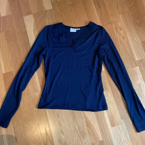 Mörkblå långärmad topp med spets - Säljer en mörkblå långärmad topp från Gina Tricot med v-ringning och fina spetsdetaljer vid halsen. Perfekt att styla med jeans eller kjol för en enkel men snygg look. Aldrig använd💞