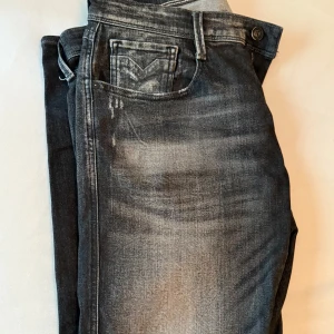 Replay Anbass svarta jeans - Säljer ett par Replay Anbass jeans i svart tvätt med snygga slitningar och diskret Replay-logga på fickan. Jeansen har klassisk femficksmodell, normal passform och raka ben. Perfekta för dig som gillar en stilren och modern look. Byxan är i storlek 34/36 men skulle säga den passar 34/35 mer pris kan diskuteras 