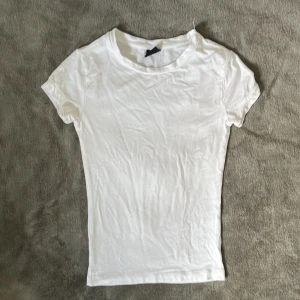 Vit basic t-shirt från Gina Tricot - Säljer en basic vit t-shirt från Gina Tricot i storlek XXS. Endast använd en gång. T-shirten har rund halsringning och korta ärmar, otroligt mjukt och skönt material. Perfekt att styla med jeans eller kjol för en clean look. Säljer även en likadan i rosa! Skriv vid fler frågor!!💓💓