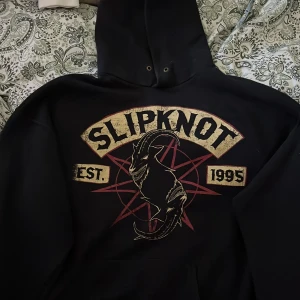Slipknot hoodie med getmotiv - Svart hoodie från Fruit of the Loom med stort Slipknot-tryck på både fram- och baksida. Har hål för tummarna. Ganska liten i storlek M på kvinna och kanske S på man.