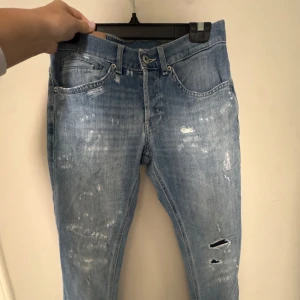 Ljusblå slitna jeans från Dondup - Säljer min brorsas dondups - ett par ljusblå jeans från Dondup med slitningar. Klassisk femficksmodell med orange detalj bak och läderpatch med dondup loggan. Jeansen har en rak passform. (I storlek 29” W29)!