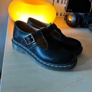 Svarta Dr. Martens Mary Jane - Klassiska svarta Mary Jane-skor från Dr. Martens i skinn med grov platt sula, ikoniska gula sömmar och rejäl spänndetalj i metall. Mina absolut DRÖMSKOR men de är tyvärr en storlek för små och kan tyvärr inte klämma i mig dem. Använda (eller försökt iallafall) ca 2 gånger så de är i väldigt fint skick!