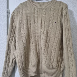 Beige kabelstickad tröja Tommy Hilfiger -  Säljer men beige Kabelstickade tröja eftersom jag har växt ur den. Den är använd ett par gånger och är i bra skick. Priset kan diskuteras 