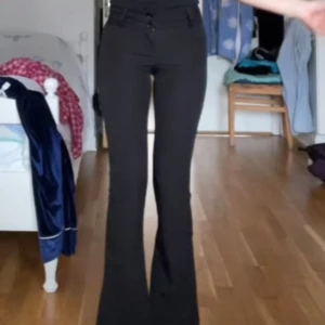 Utsvängda kostymbyxor  - Snygga svarta kostymbyxor som är utsvängda. Byxorna har två knappar framtill, bälteshällor och en ficka med knapp bak. Nytt pris 500kr men säljer för 300kr då jag vill bli av med dom. Har använt dom endast en gång, kp för fler frågor🫶🏼