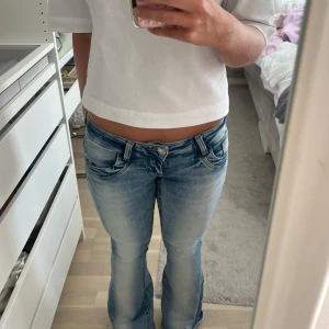 Gina 14+ jeans - Säljer ett par ljusblå bootcut jeans med snygg slitning och låg midja från Gina 14+. Midjemåttet är 38 cm rakt över men stretchiga så passar större och mindre. Helt slutsålda🤍