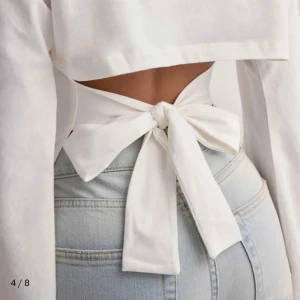 Vit långärmad topp med knyt i ryggen - Trendig vit topp med långa vida ärmar och snygg knytning i ryggen som ger en öppen rygg-detalj. Toppen har en rak passform och är tillverkad i ett mjukt bomullsmaterial. Perfekt för dig som vill ha en stilren men unik look. Aldrid använd💕