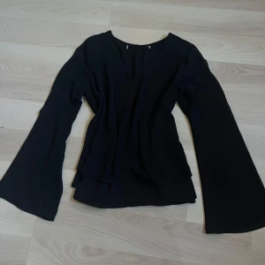 Svart blus med v-ringning - Svart blus med v-ringad hals och vida armar. Den är i ett tunnare mesh-liknande material men har dubbla lager. Endast andvänd fåtal gånger för länge sedan, inga skador eller defekter på plagget💗köparen står för frakt🫶