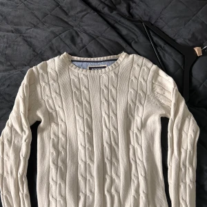 Vit kabelstickad tröja från Bondelid - Säljer en vit kabelstickad tröja från Bondelid i 100% bomull. Tröjan har rund halsringning, lång ärm och klassiskt kabelmönster som ger en snygg och tidlös look. Perfekt att matcha med jeans, old money stil. 