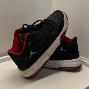 Svarta Jordan sneakers  - Snygga svarta Jordan sneakers med röda detaljer och vit sula. Skorna har klassisk Jumpman-logga på sidan, snörning och meshpaneler för extra andningsförmåga. Perfekta för dig som gillar sportig och streetinspirerad stil.