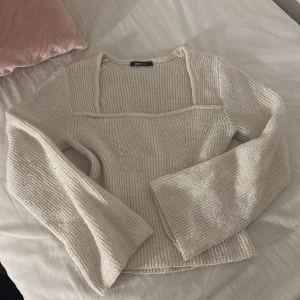 Beige stickad tröja från Gina Tricot - Superfin beige stickad tröja från Gina Tricot med breda ärmar och fyrkantig ringning. Tröjan har ett snyggt ribbat mönster. Passar dig som gillar en chill men ändå trendig look.