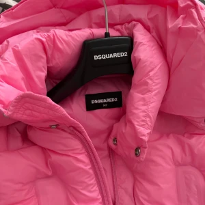 Rosa pufferjacka från DSQUARED2 - Säljer en riktigt fet rosa pufferjacka från DSQUARED2. Jackan har hög krage, dragkedja framtill och coola quiltade detaljer med Dsquared2-logga i tyget. Perfekt för dig som vill sticka ut i vinter och hålla dig varm med stil. Sitter som en XS passar mig som är 174, nypris 6000kr