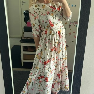 Vit blommig långklänning med trekvartsärm - Superfin långklänning i vitt med färgglatt blommönster i rött, gult och grönt. Klänningen har rund halsringning, trekvartsärmar och ett härligt fall med markerad midja. Perfekt för sommarens alla tillfällen!Helt ny,bara tvättad 