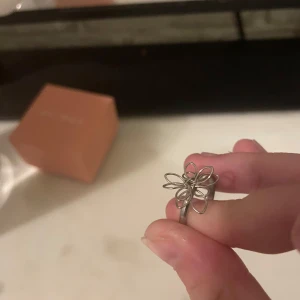 Silvrig ring med blomformad design - Unik silvrig ring med en cool blomformad design i metalltråd. Perfekt för dig som vill sticka ut med ett smycke som känns både trendigt och lekfullt. Passar till alla tillfällen när du vill addera lite extra stil till din look.