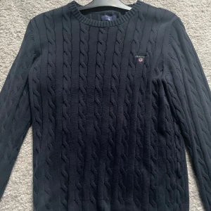 Marinblå kabelstickad tröja GANT - Kabelstickad marinblå tröja från GANT i premium bomull. Pris går att diskutera 