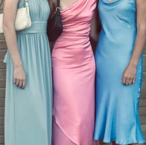 Rosa satin långklänning  - Säljer en snygg långklänning i glansigt rosa satin med oneshoulder-design och draperad överdel. Klänningen har figurnära passform och en elegant slits framtill. Priset går att diskutera. 