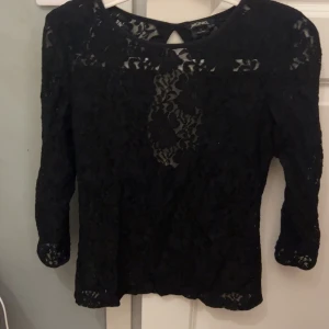 Svart spetsblus med öppen rygg - Säljer en svart blus från Monki i spet. Toppen har trekvartsärm och en snygg öppen ryggdetalj. Skriv till mig vid frågor eller funderingar❤️🥰