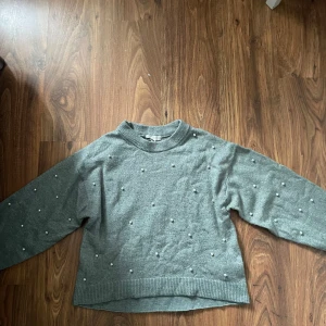 Grön stickad tröja med pärlor H&M - Superfin grön stickad tröja från H&M med pärldetaljer över hela tröjan. Tröjan har rund halsringning, ribbade muddar och lång ärm. Perfekt för dig som gillar en enkel men ändå lite extra look.
