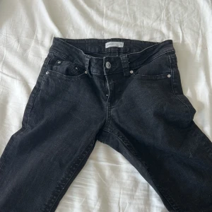 Svarta bootcut jeans med fickdetaljer - Svarta jeans med bootcut passform från Perfect Jeans. Klassisk femficksmodell med snygga ficklock och silverfärgade knappar bak. Jeansen har normal midja och är tillverkade i mjukt denimtyg. Perfekta för en avslappnad men trendig look.