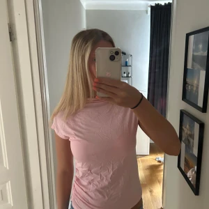 Ljusrosa kortärmad topp - Enkel och söt ljusrosa topp med korta ärmar och rund hals. Tunt och mjukt material som känns skönt mot huden. Perfekt att matcha med jeans eller kjol för en chill look.