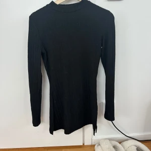 Svart ribbad långärmad tröja med slits - Svart långärmad tröja med ribbad struktur och hög hals. Tröjan har en snygg slits på sidan. Skriv privat för mer bilder 