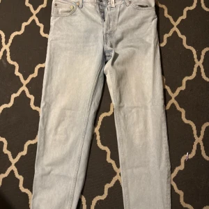 Ljusblå jeans från Weekday 30/32 - Säljer ett par ljusblå jeans från Weekday i modellen Dami Relaxed Tapered. Jeansen har klassisk femficksdesign, normal passform upptill och smalnar av nedtill. Tillverkade i bomull med snygg tvättad look och dragkedjegylf.