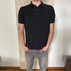 Svart pikétröja från Ralph Lauren - Klassisk svart pikétröja från Ralph Lauren. Storleken är M och skicket är bra